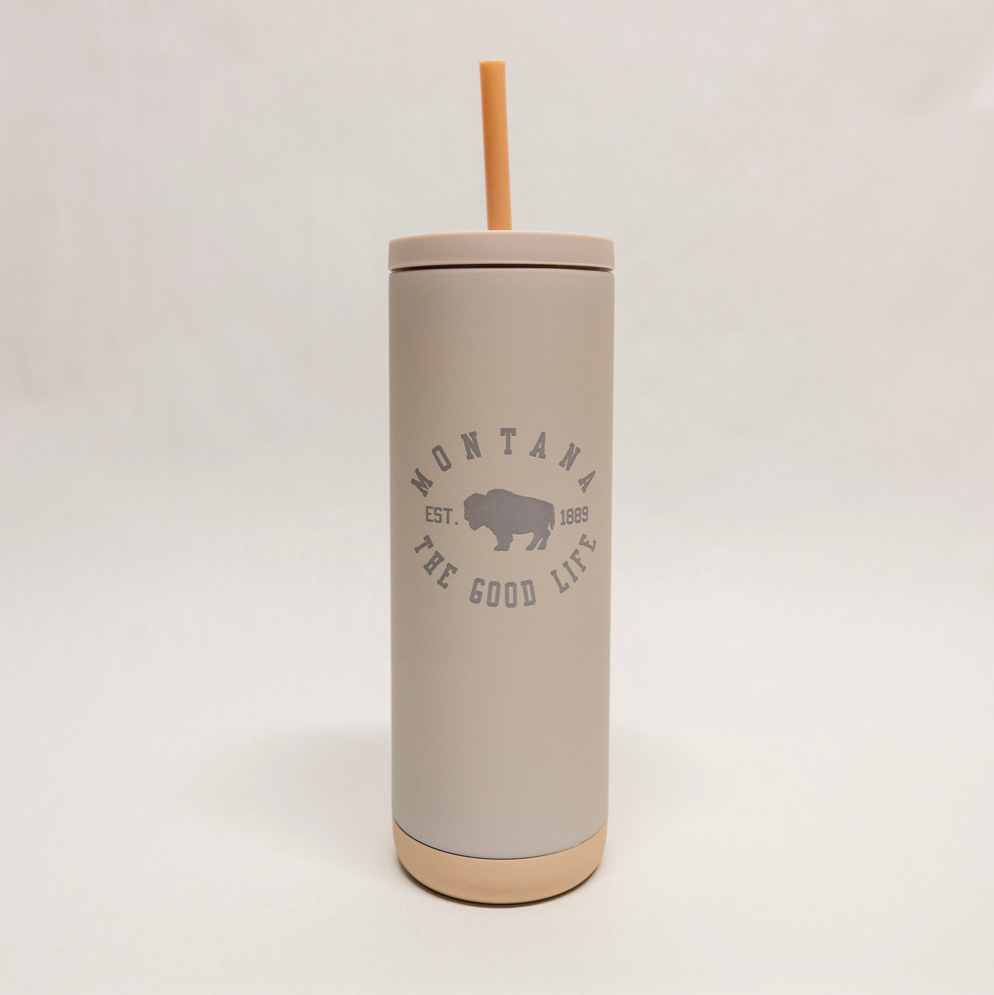 Gray tumbler with straw lid featuring 'Montana the Good Life' text on a light gray background