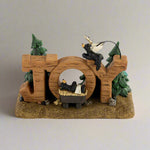 Decorative figurine with 'joy' spelling and bear and tree designs on a white background