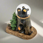 Glowing bear-themed snow globe with trees and footprints on a white background