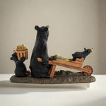 Bear family figurine with a mother bear and two cubs carrying a wooden cart with vegetables on a white background.