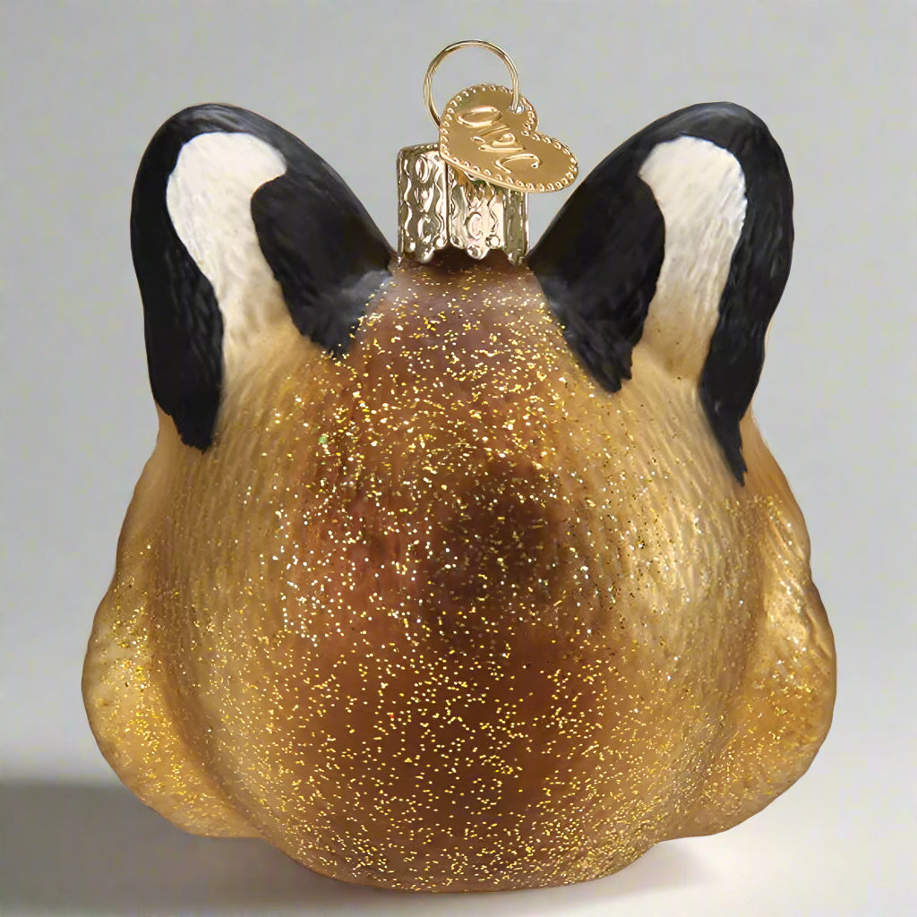 Glass ornament shaped like a bobcat face with black ears and a gold glittery body on a white background