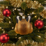 Glass ornament shaped like a bobcat face with black ears and a gold glittery body on a white background