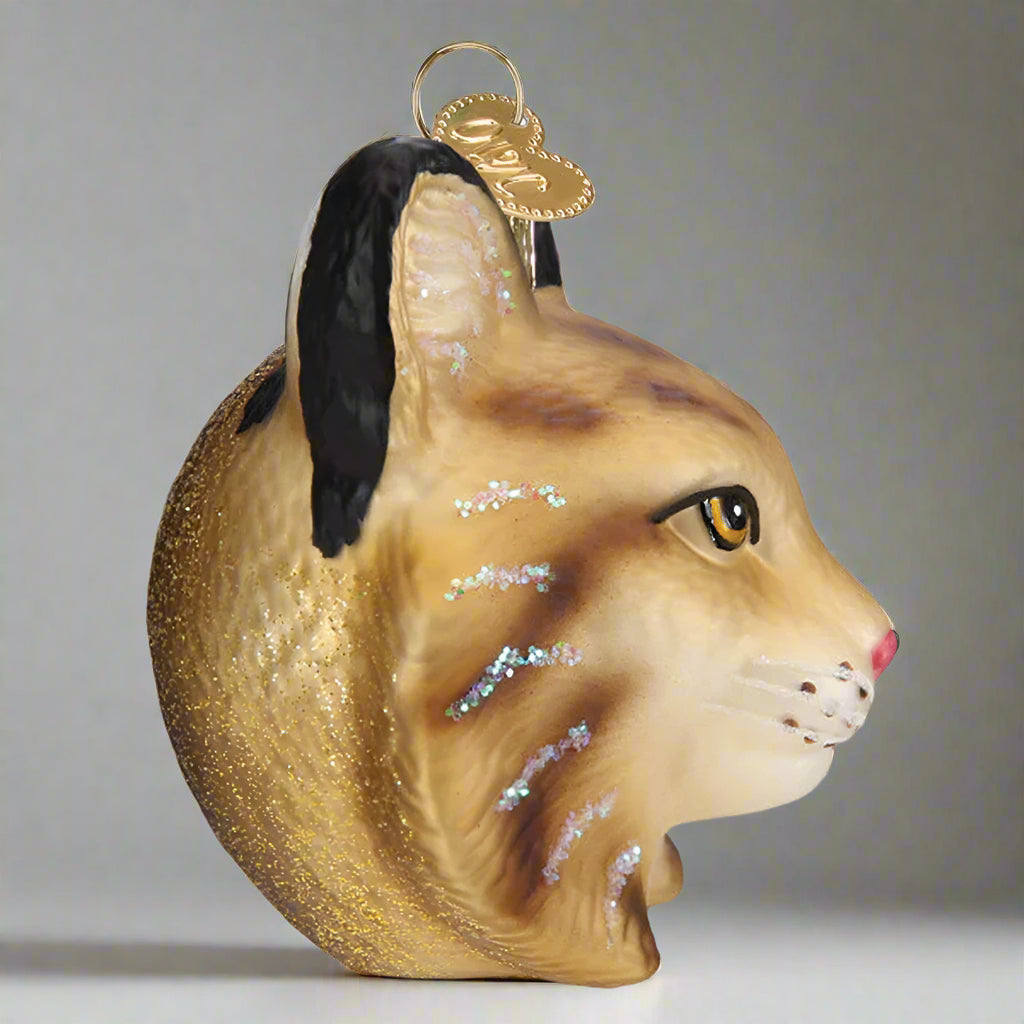 Glass ornament shaped like a bobcat head with a gold background