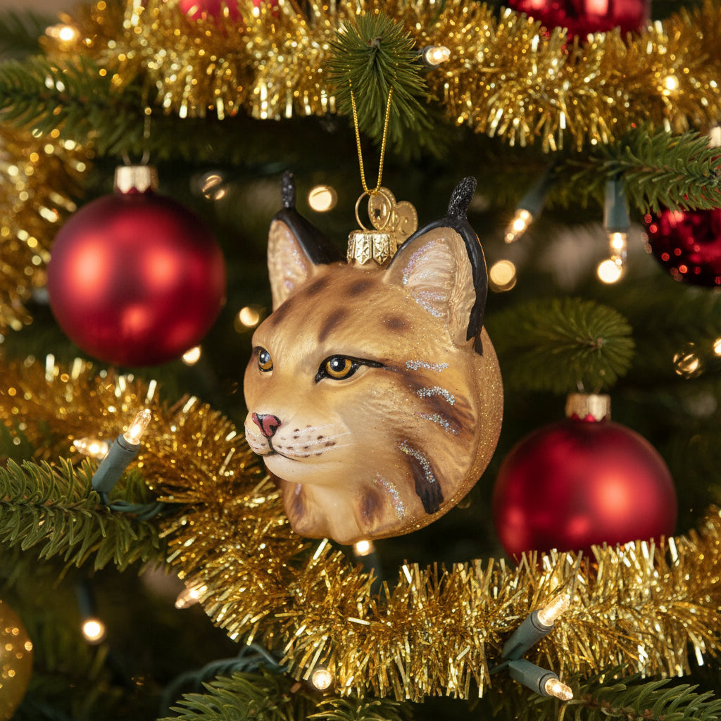 Glass ornament shaped like a bobcat head with a gold background