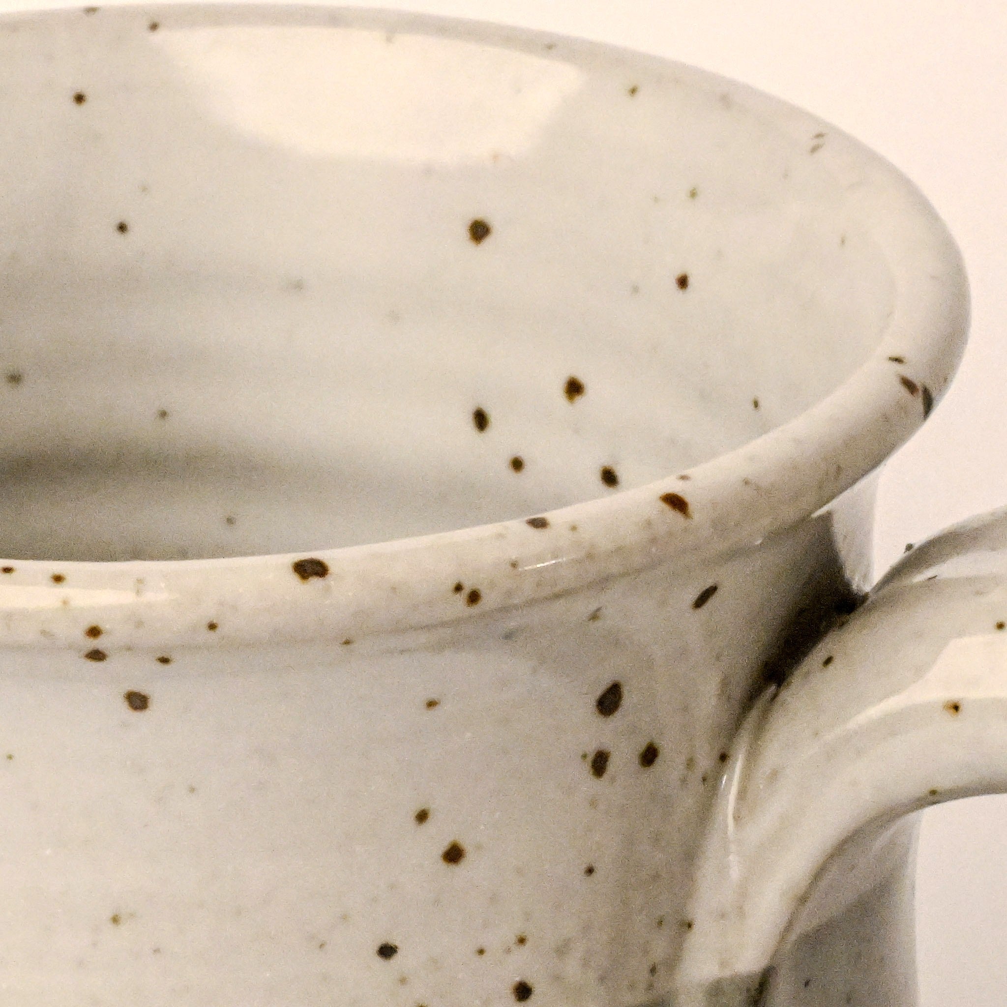 Close-up of a ceramic mug with speckled pattern on a neutral background