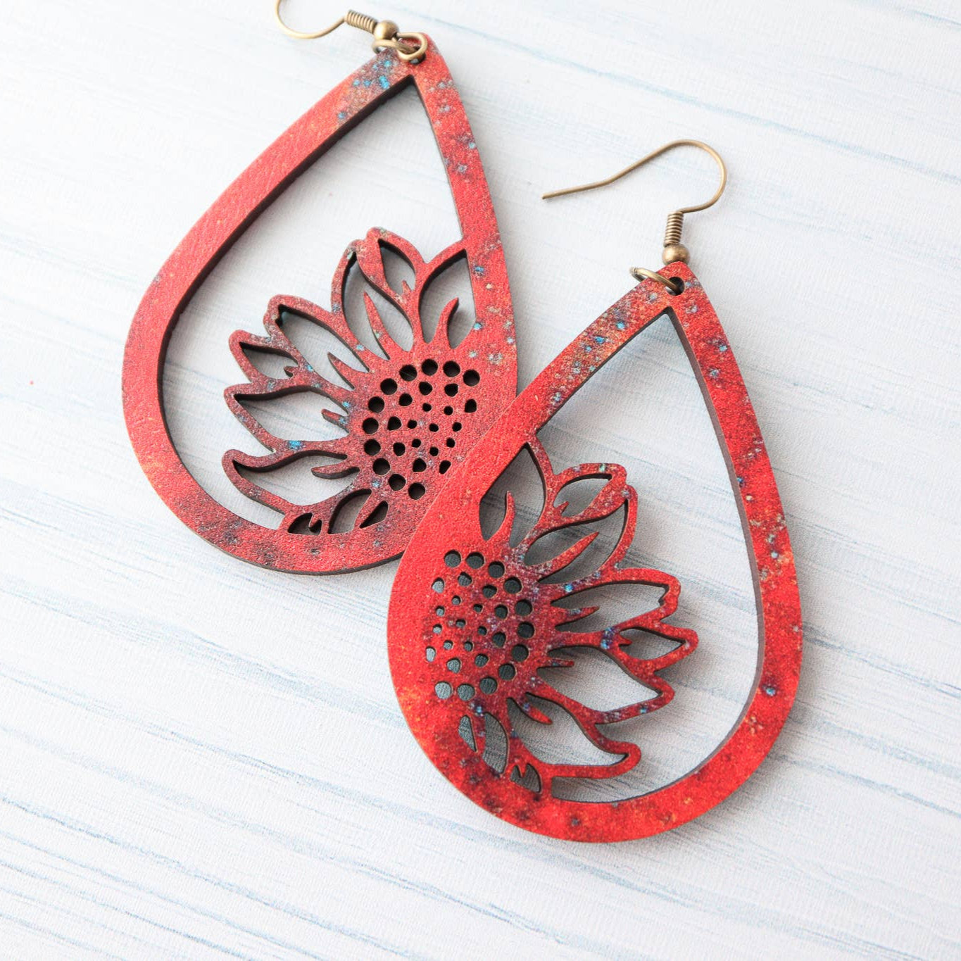 Red teardrop-shaped earrings with floral cutout design on a white background