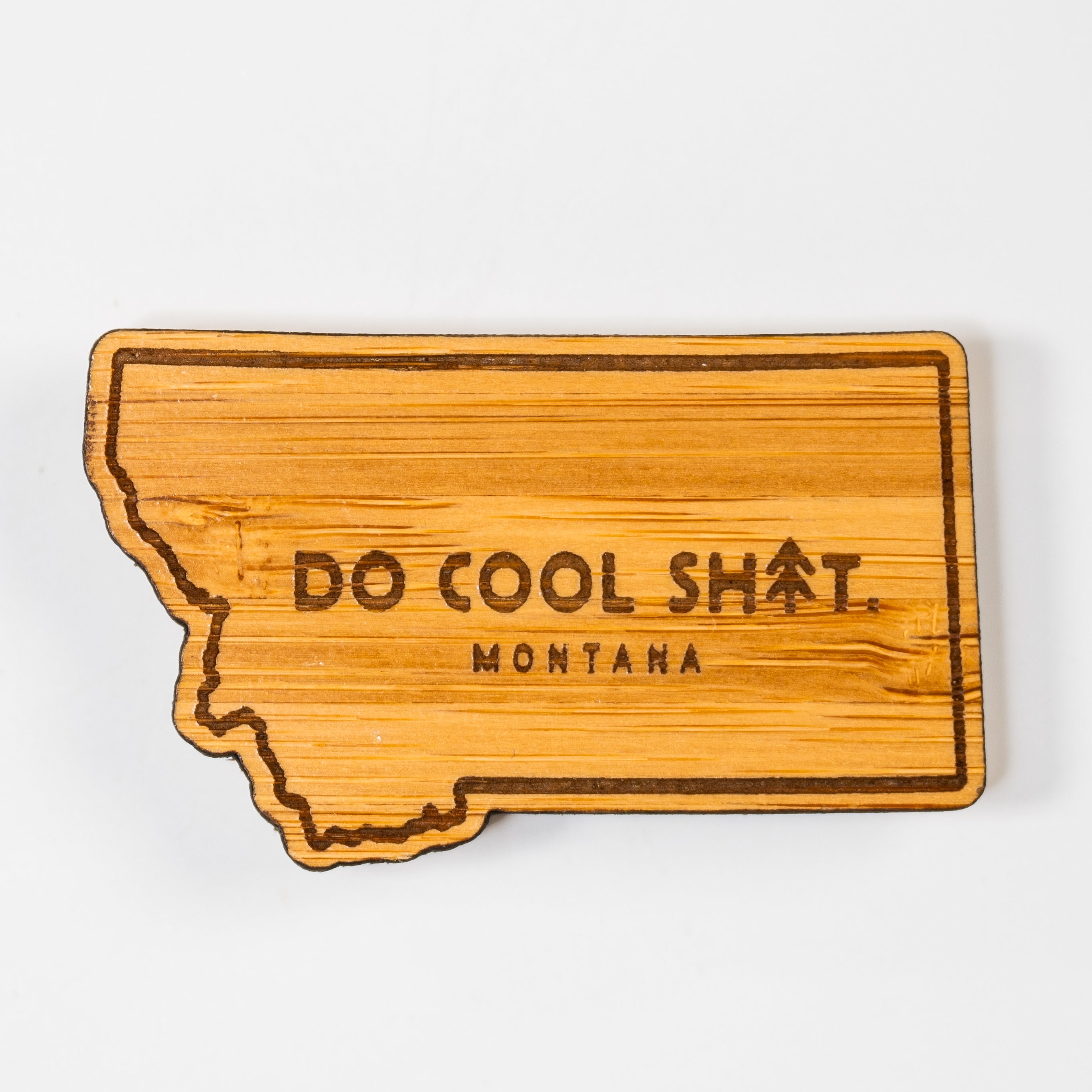 Wooden state-shaped magnet with 'Do Cool Sh*t. Montana' text on a white background