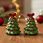 Green Christmas tree-shaped candles with red bows on a white background
