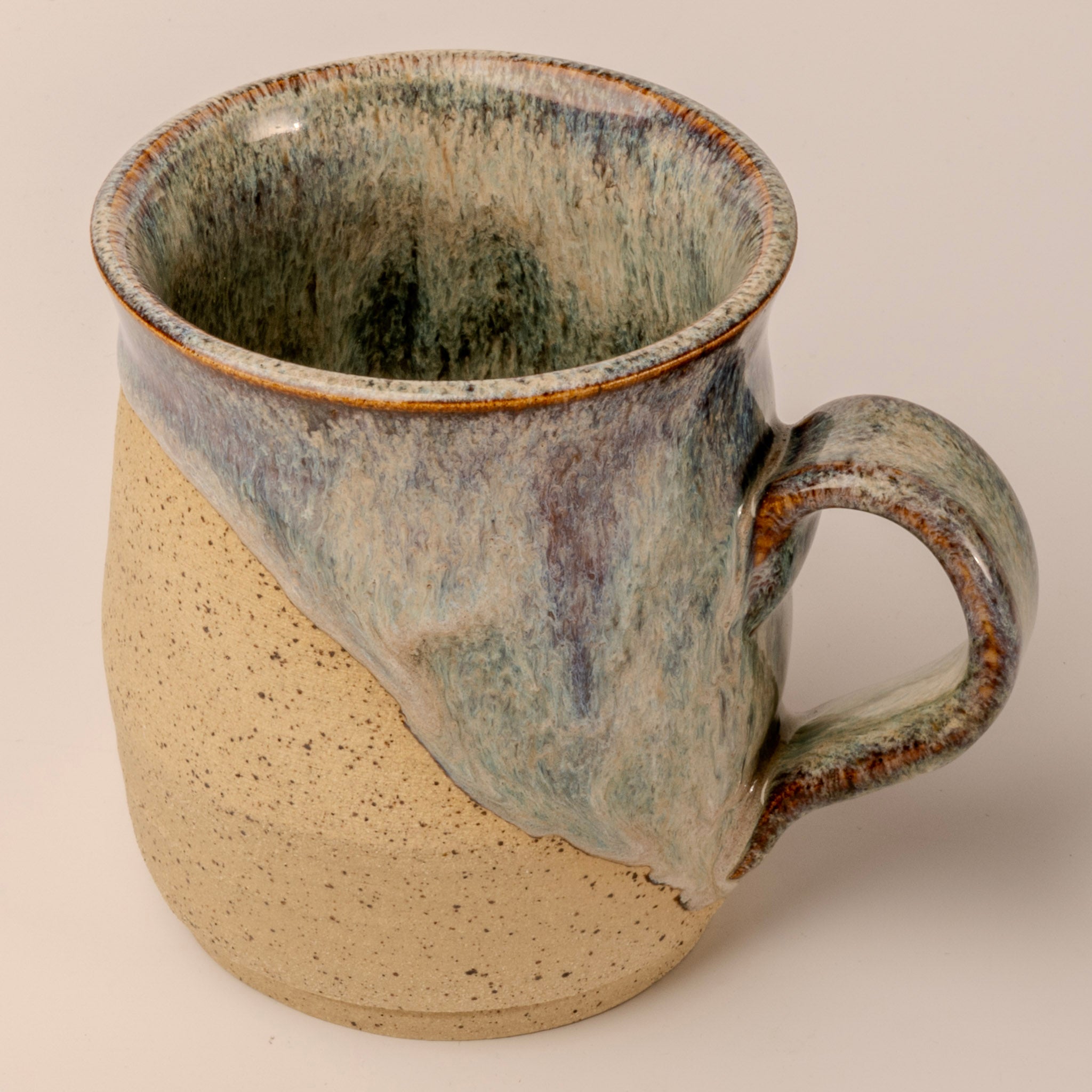 Handmade ceramic mug with a textured surface on a plain background