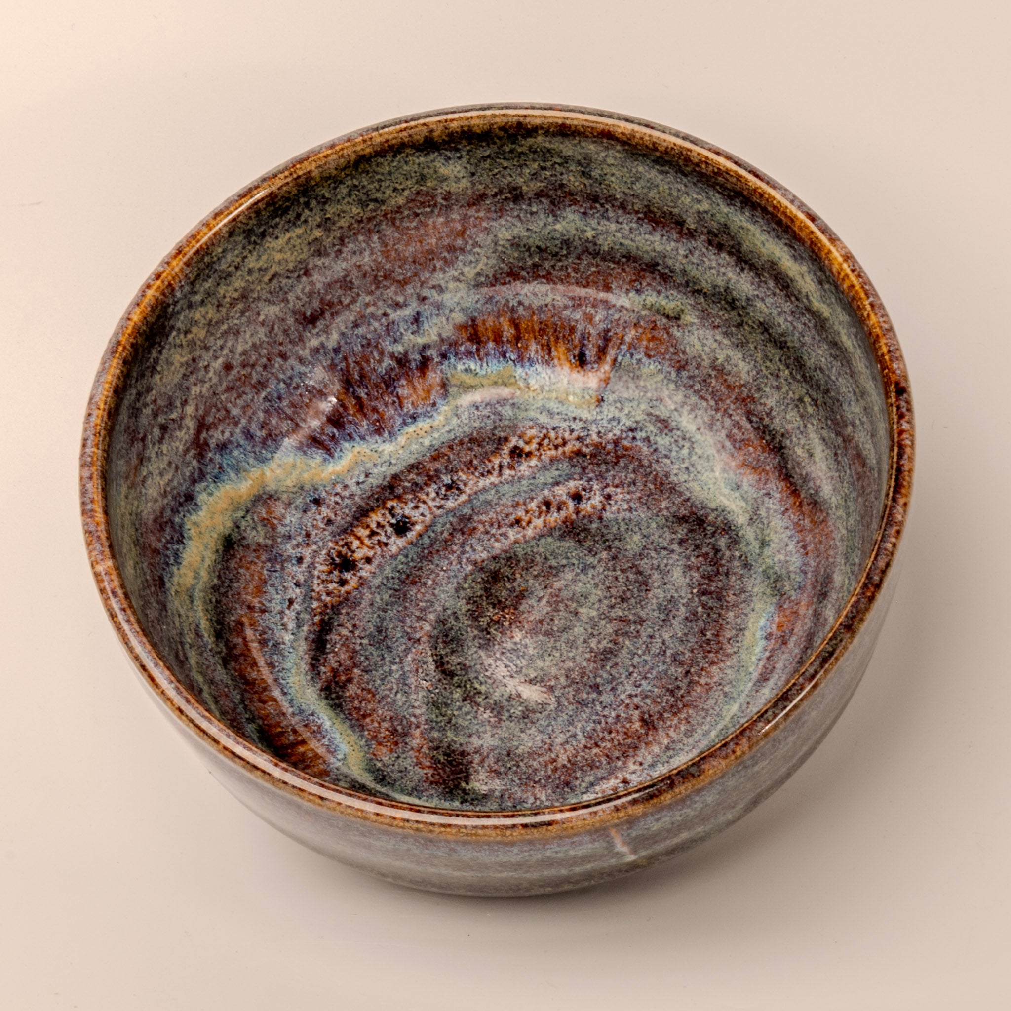 Ceramic bowl with swirling brown and blue pattern on a beige background