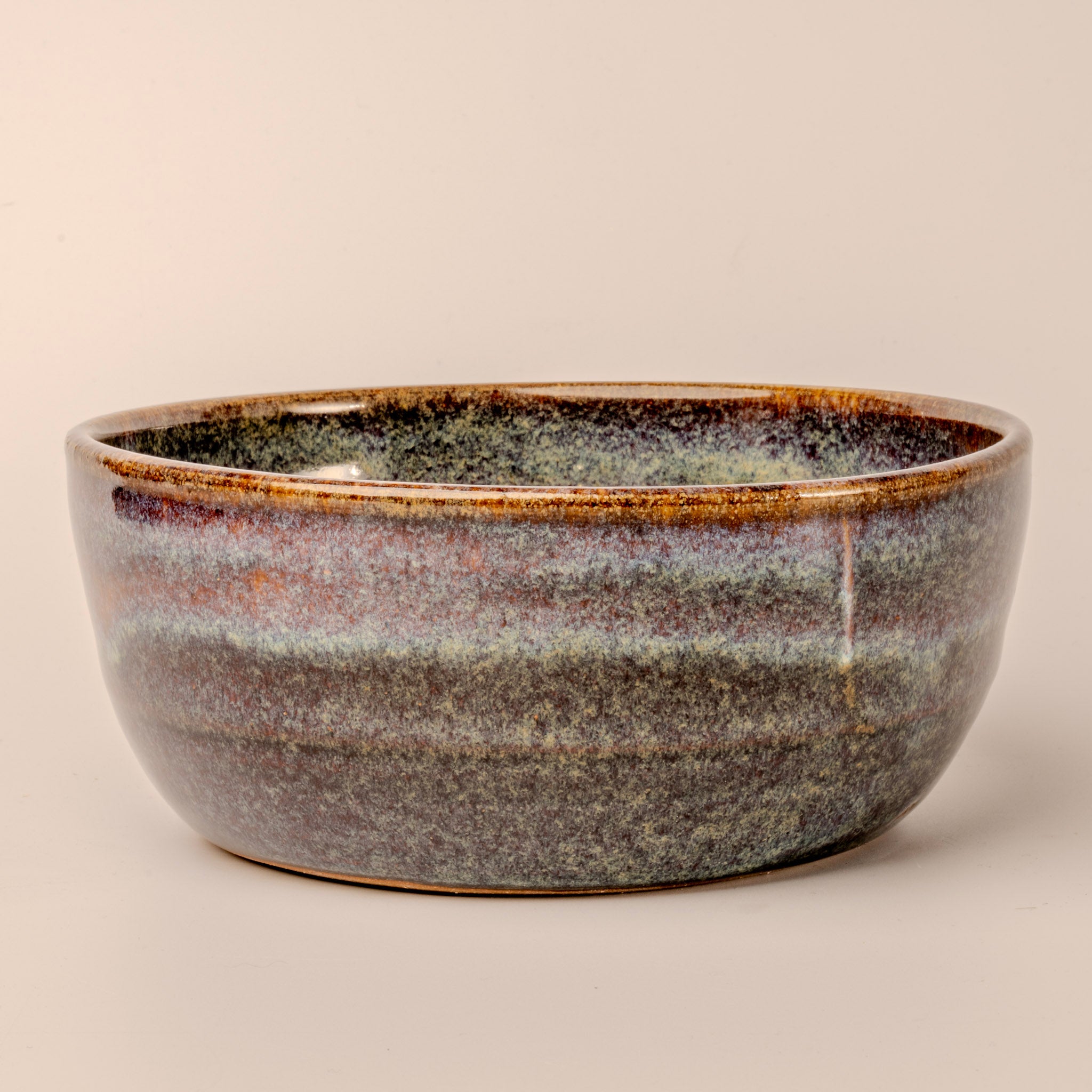 Ceramic bowl with speckled glaze on a beige background