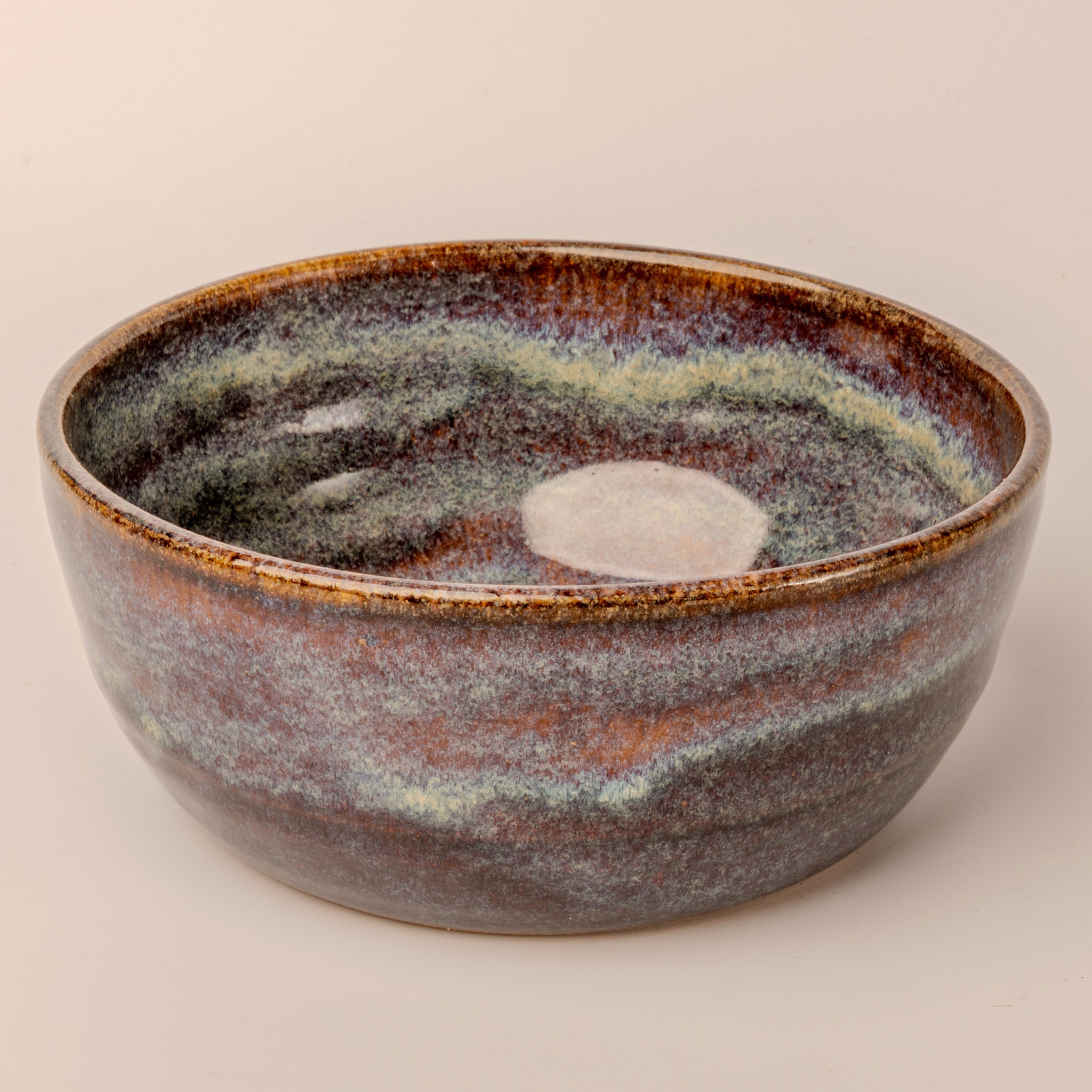 Ceramic bowl with multicolored glaze on a beige background