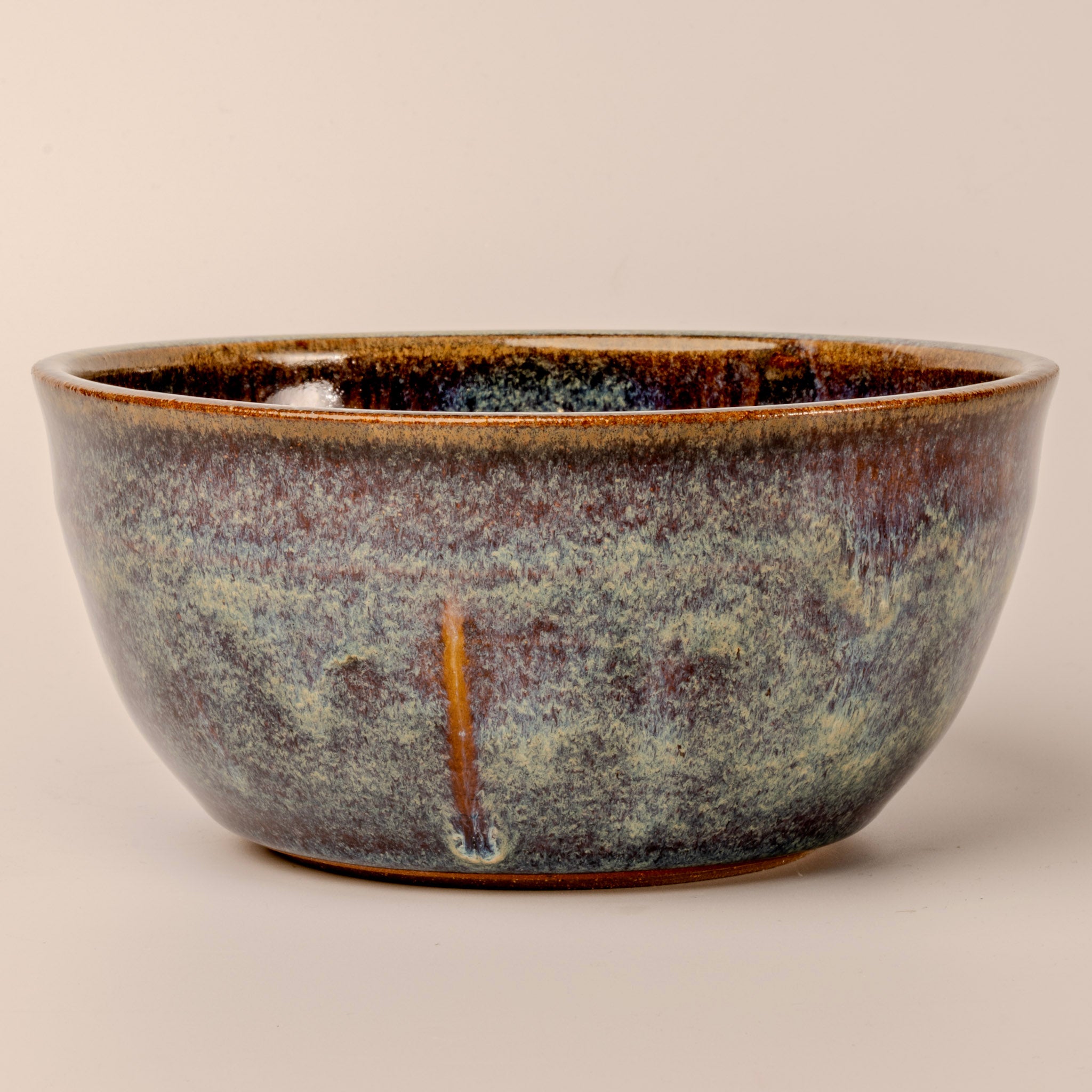 Stoneware bowl with a speckled glaze on a beige background