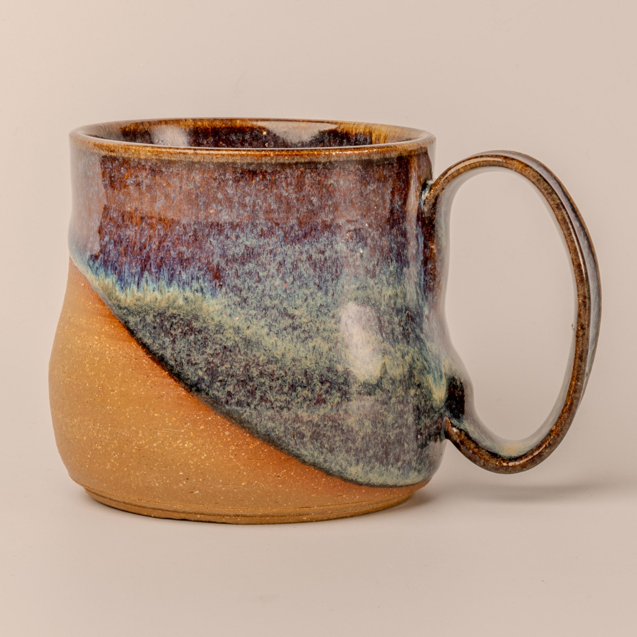 Ceramic mug with multicolored glaze on a beige background