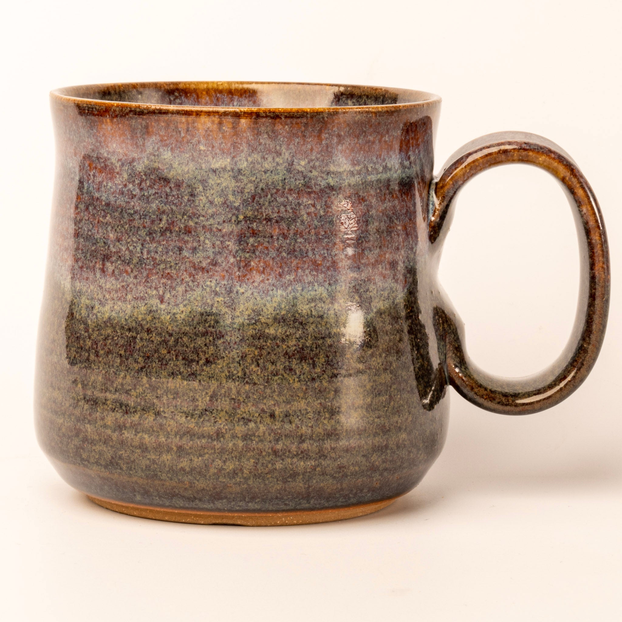 Ceramic mug with brown and black speckled glaze on a white background