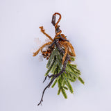 Decorative branch with greenery and brown twine on a light gray background