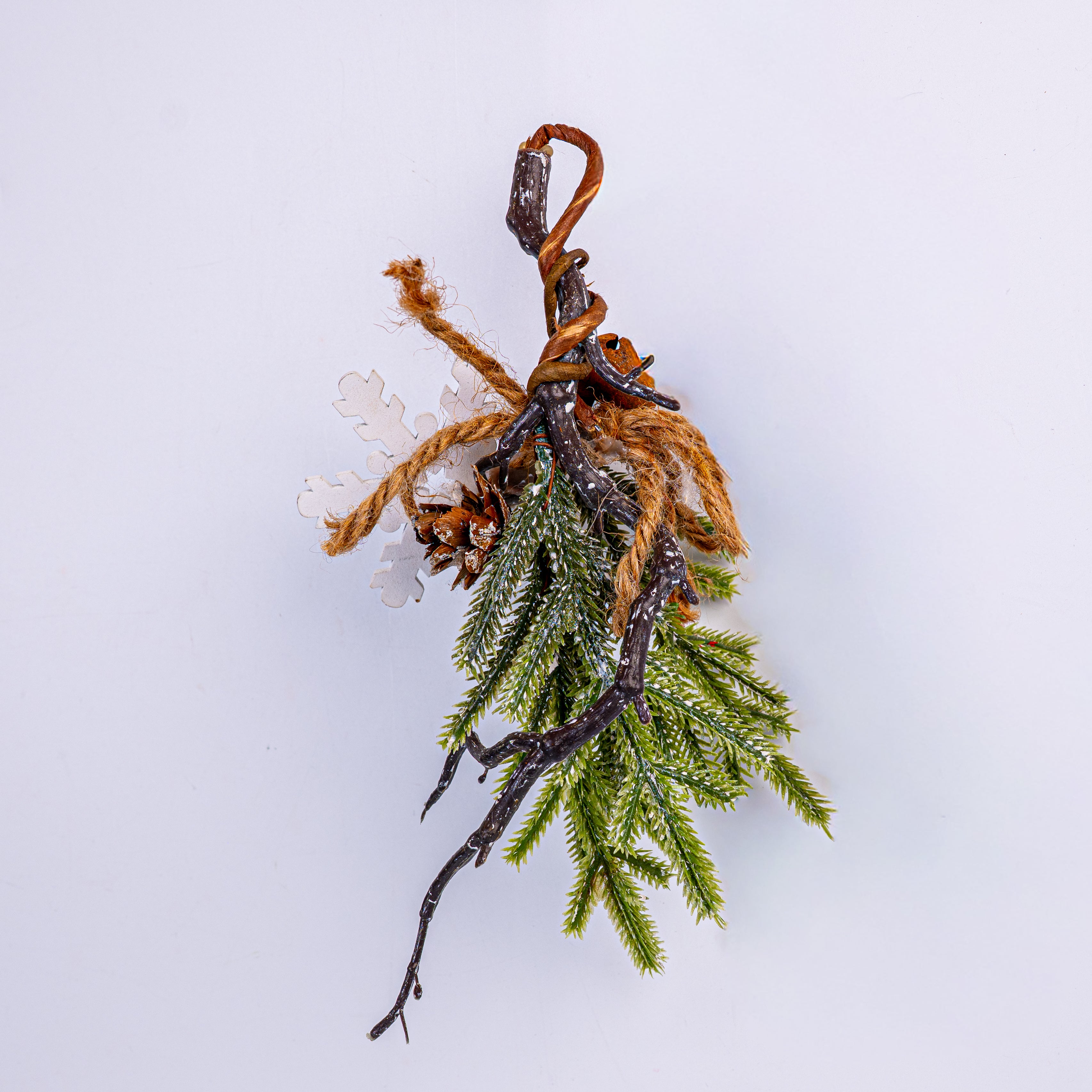 Decorative branch with greenery and brown twine on a light gray background