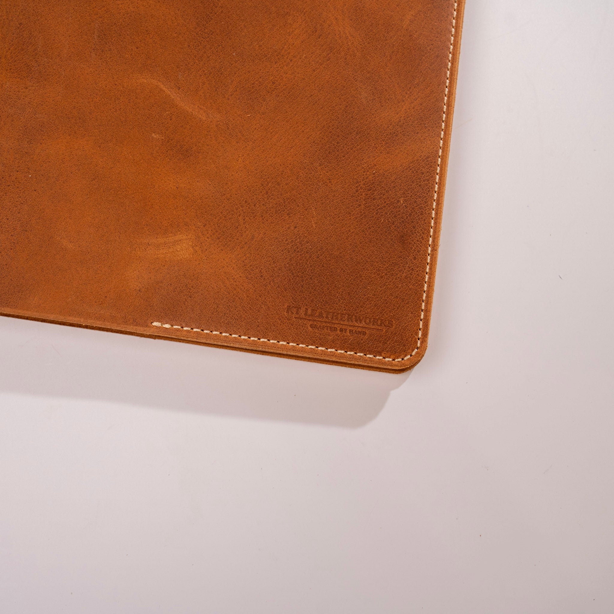 Brown leather product with visible stitching on a light gray background
