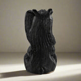 Black resin sculpture of a bear on a white background