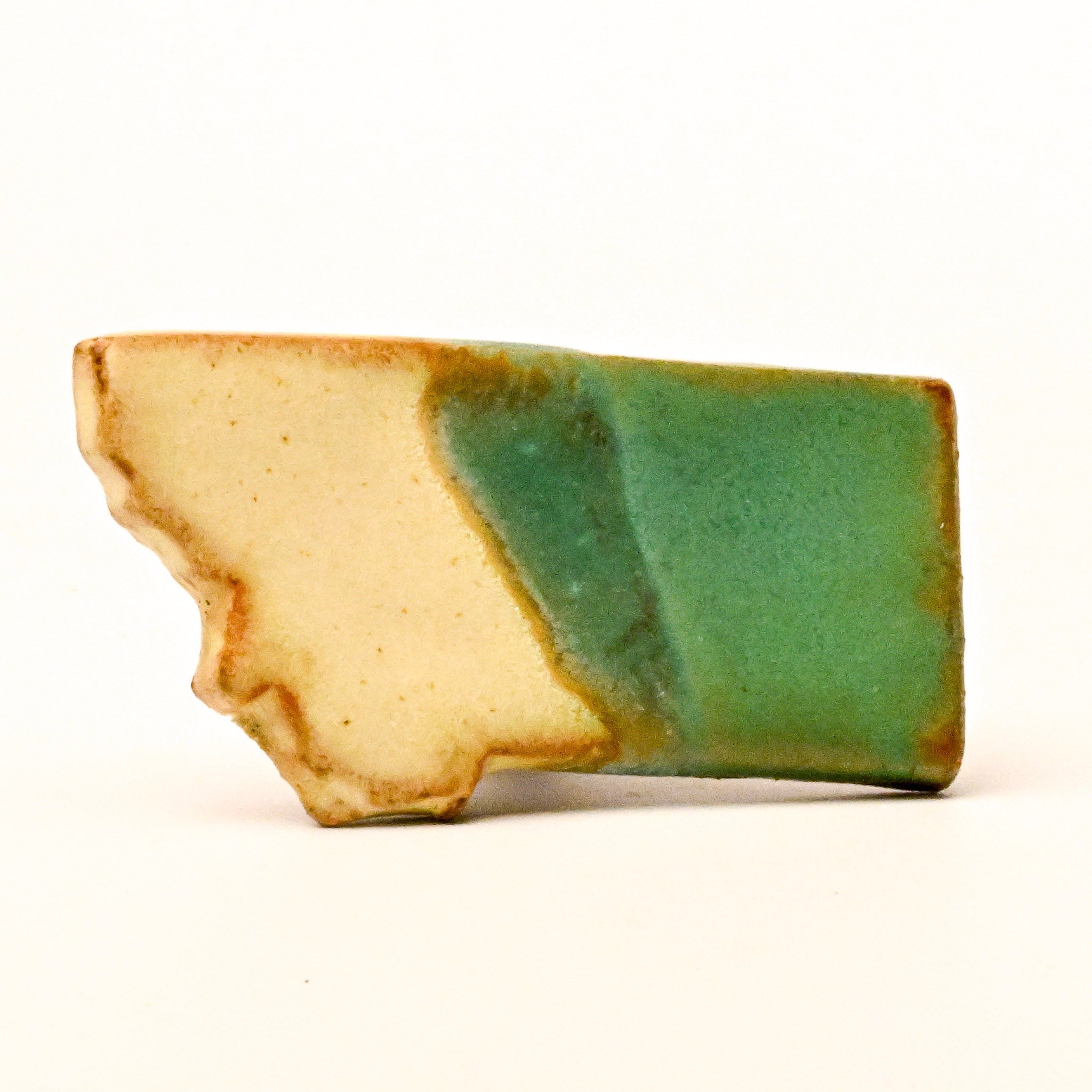 Ceramic magnet with green and beige colors on a white background