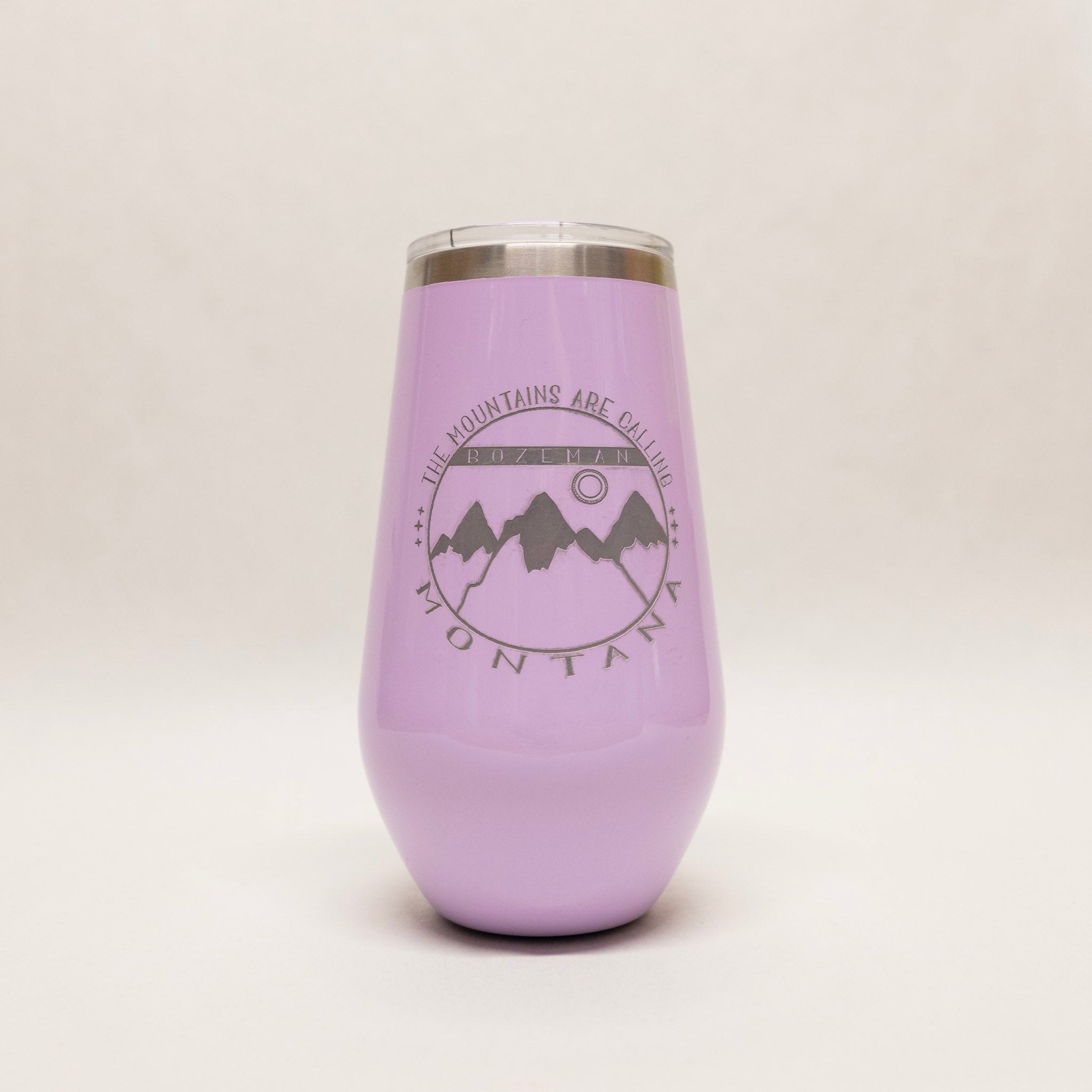 Purple tumbler with mountain design and text on a light gray background