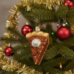 Glass ornament shaped like a slice of pie with whipped cream on a white background