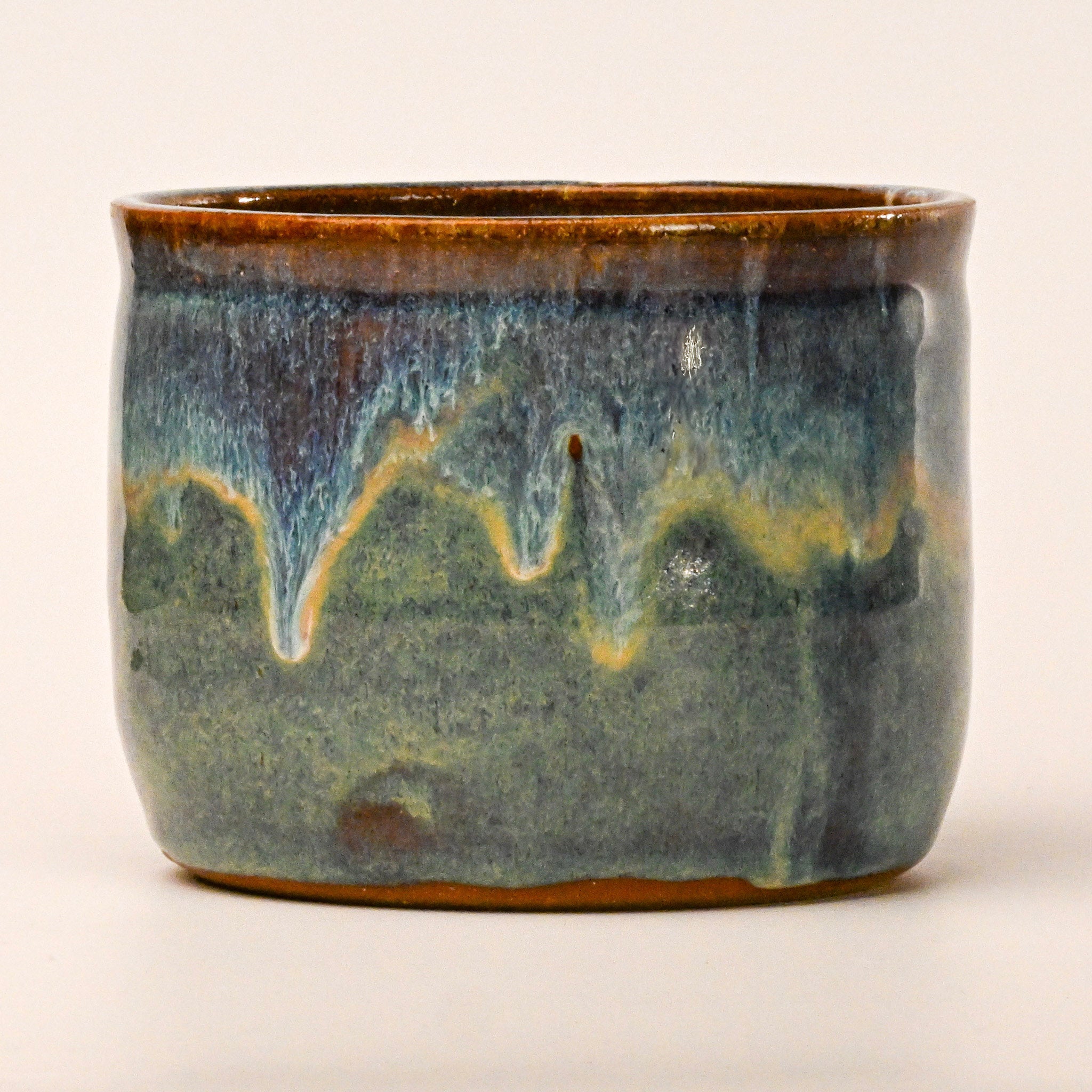 Ceramic pot with blue and brown glaze on a white background