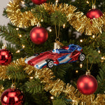 Glass ornament of a red and blue race car on a white background