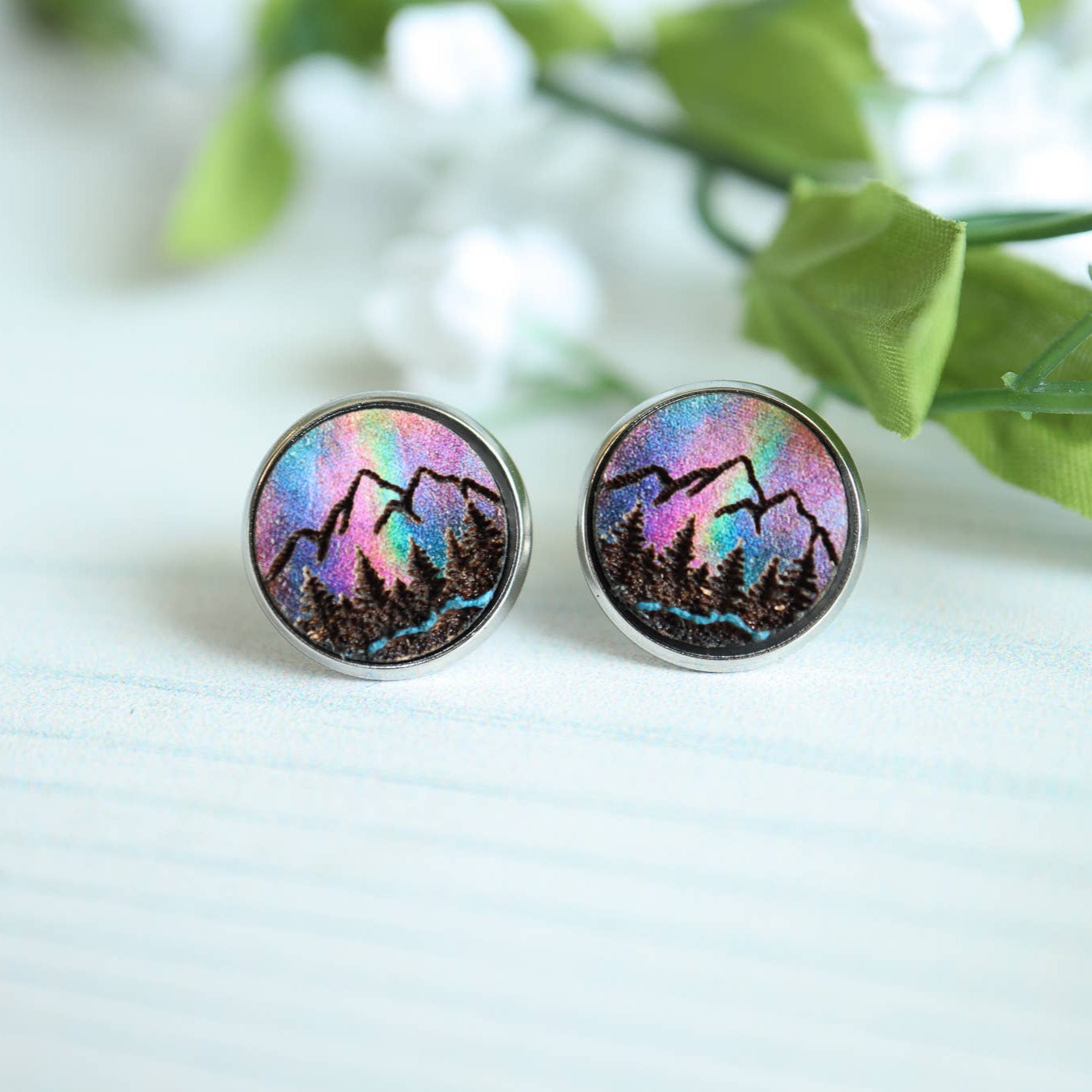 Pair of round earrings with mountain design on a light background
