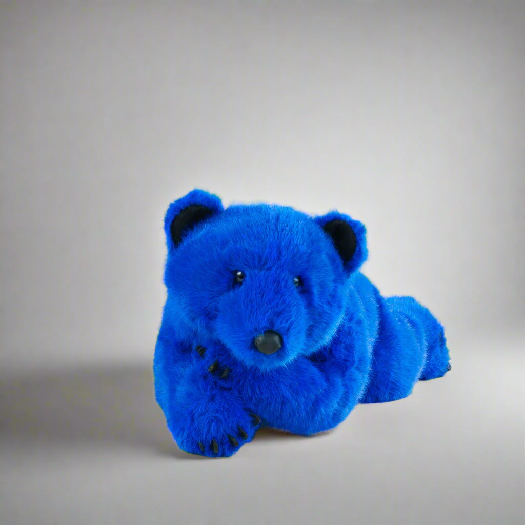 Blue teddy bear on a white surface with a gray background