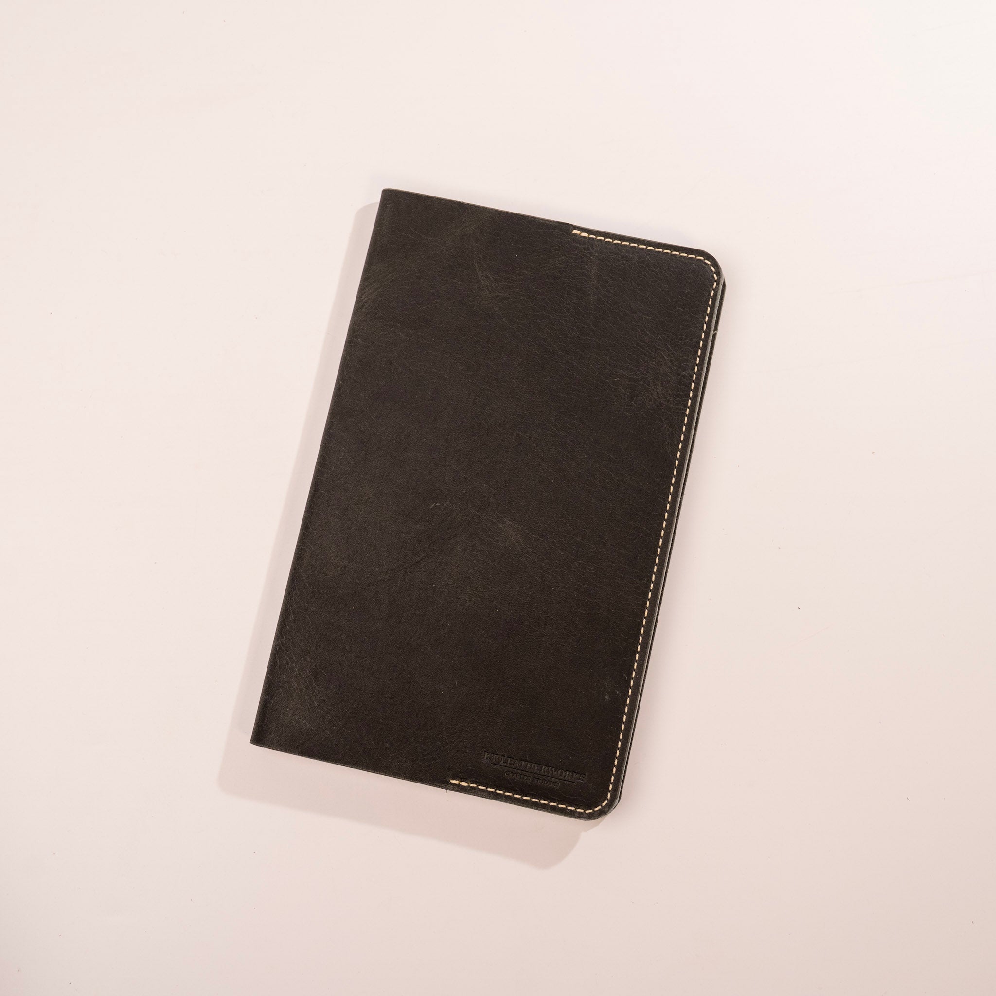 Black leather notebook on a light beige background