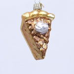 Glass ornament shaped like a slice of pie with whipped cream on a white background