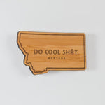 Wooden state-shaped magnet with 'Do Cool Sh*t. Montana' text on a white background
