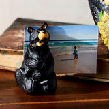 Decorative heart-shaped object with bear and sunflower design, accompanied by a small bear figurine and a beach scene card.