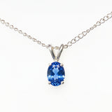A silver chain necklace with a oval-cut blue gemstone pendant in a silver setting, shown against a plain white background.
