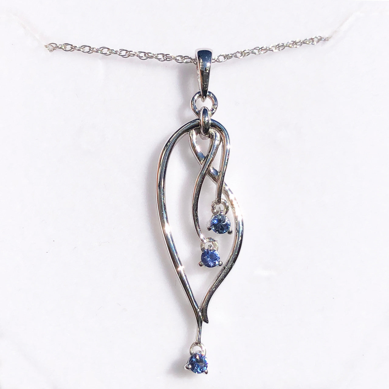 Silver pendant with blue gemstones on a white background