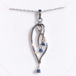Silver pendant with blue gemstones on a white background