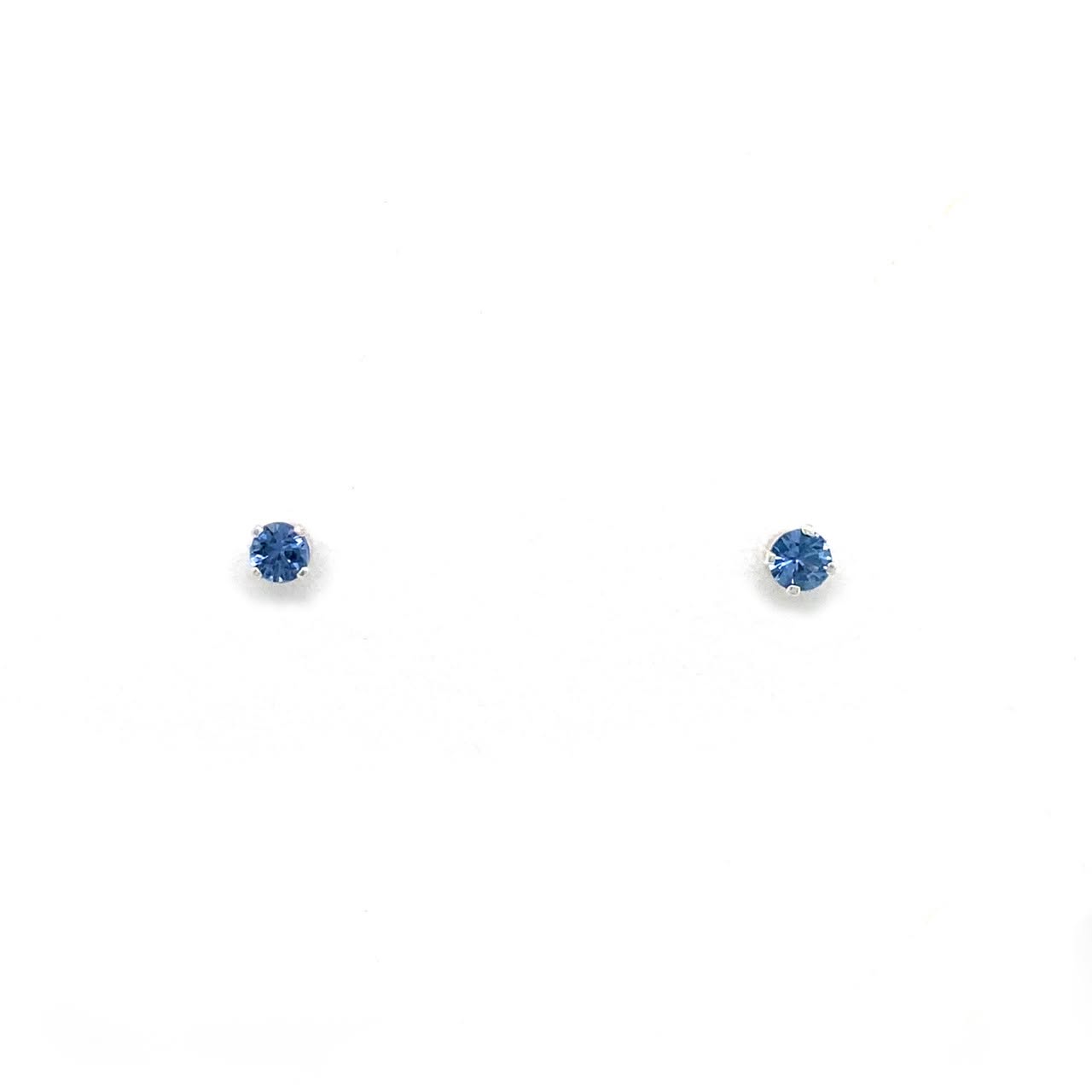 A pair of small round stud earrings with deep blue gemstones in silver settings, displayed on a clean white background.