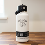 White water bottle with black lid on a wooden surface, featuring 'Bozeman Montana' branding.
