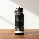 Black water bottle with Montana branding on a wooden surface