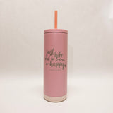Pink tumbler with a straw on a light beige background