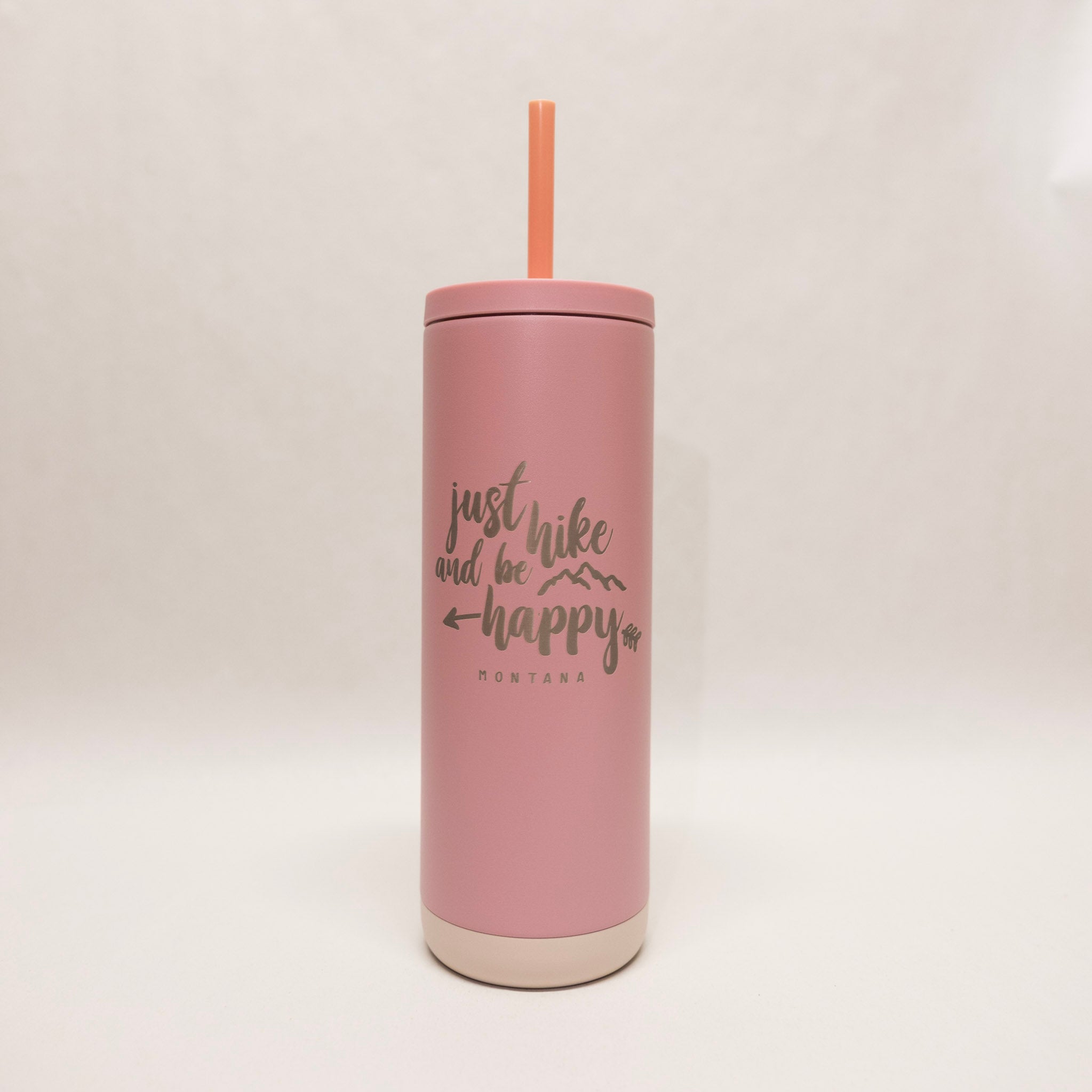 Pink tumbler with a straw on a light beige background
