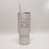 White tumbler with an engraved design with mountains and trees and the words "It's all good in the woods"