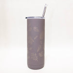 Gray tumbler with leaf pattern and straw on a white background