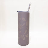 Gray tumbler with leaf pattern and straw on a white background