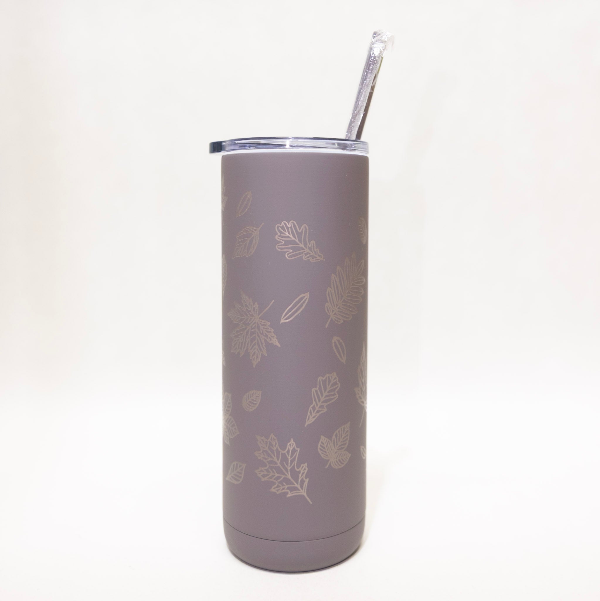 Gray tumbler with leaf pattern and straw on a white background