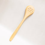 Wooden spoon with engraved text on a light gray background