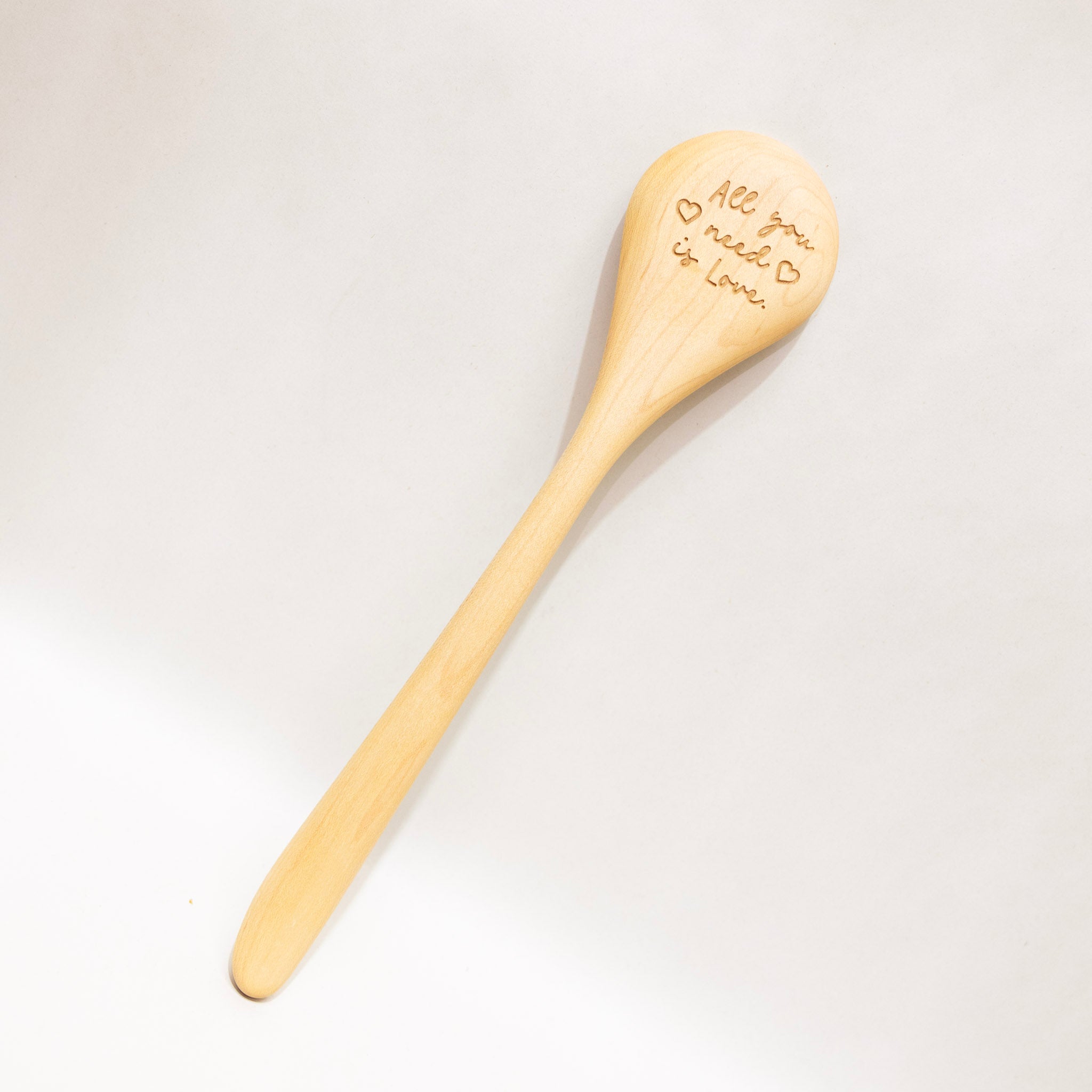 Wooden spoon with engraved text on a light gray background