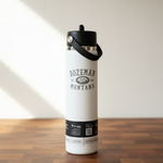 White water bottle with black lid and 'Bozeman Montana' branding on a wooden surface.