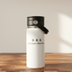 White insulated bottle with black lid and handle on a wooden surface